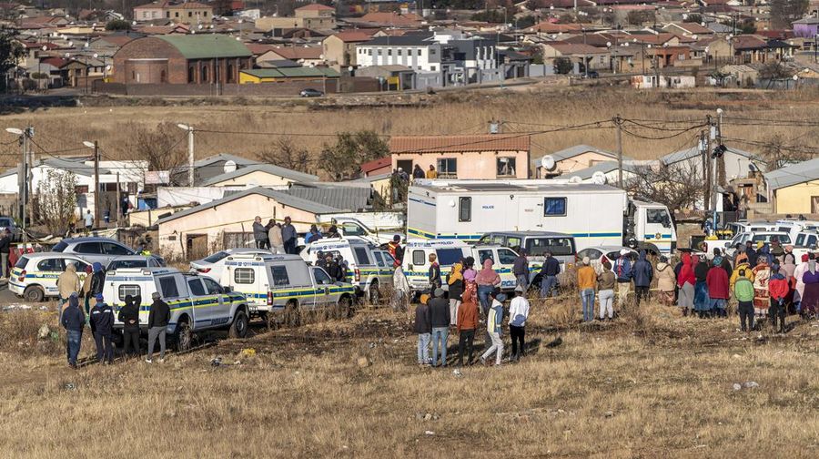 SOWETO, SOUTH AFRICA - JULY 10:  A woman reacts as securtiy forces and forensic service inspect the scene of a mass shooting in Soweto, South Africa, on July 10, 2022. Fourteen people have been killed in a mass shooting at a bar in Soweto township near Johannesburg, police said Sunday. (Photo by Ihsaan Haffejee/Anadolu Agency via Getty Images)