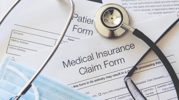 Ilustrasi Asuransi Kesehatan Medical Insurance claim form with stethoscope and surgical face mask. There are also other pieces of paperwork on the desk including a patient form