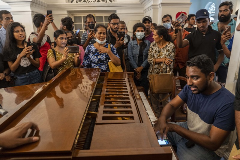 People queue up to visit President Gotabaya Rajapaksa's office for the second day after it was stormed in Colombo, Sri Lanka, Monday, July 11, 2022. Sri Lanka is in a political vacuum for a second day Monday with opposition leaders yet to agree on who should replace its roundly rejected leaders, whose residences are occupied by protesters, angry over the country's economic woes. (AP Photo/Eranga Jayawardena)