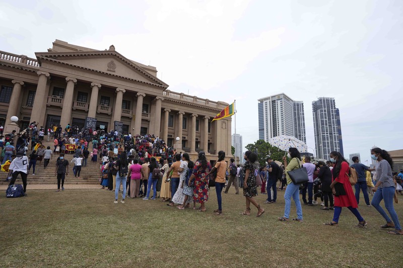 People queue up to visit President Gotabaya Rajapaksa's office for the second day after it was stormed in Colombo, Sri Lanka, Monday, July 11, 2022. Sri Lanka is in a political vacuum for a second day Monday with opposition leaders yet to agree on who should replace its roundly rejected leaders, whose residences are occupied by protesters, angry over the country's economic woes. (AP Photo/Eranga Jayawardena)