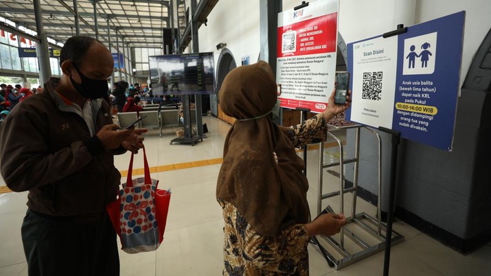 Sejumlah penumpang kereta KRL melakukan scan PeduliLindungi di Stasiun Pasar Senen, Jakarta, Selasa (12/7/2022). Pemerintah telah menerbitkan patokan perjalanan terbaru merespons kenaikan kasus COVID-19. Aturan-aturan perjalanan terbaru bakal mulai bertindak mulai 17 Juli 2022 mendatang. (CNBC Indonesia/Tri Susilo)