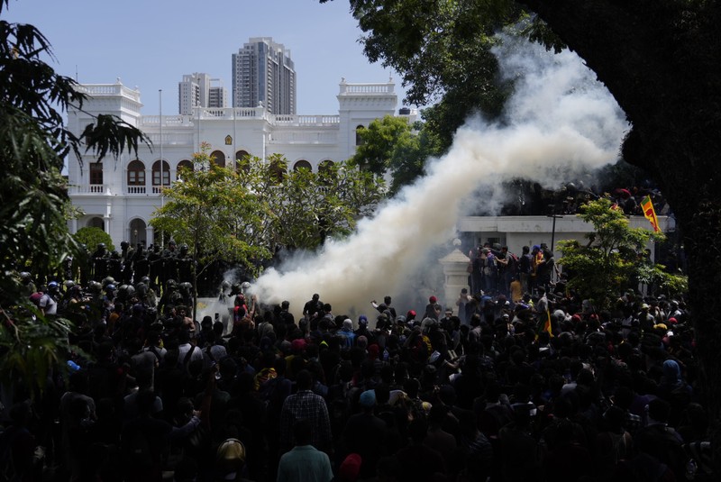 Police use teargas as Sri Lankan protesters storm the compound of prime minister Ranil Wickremesinghe 's office, demanding he resign after president Gotabaya Rajapaksa fled amid economic crisis in Colombo, Sri Lanka, Wednesday, July 13, 2022. (AP Photo/Rafiq Maqbool)