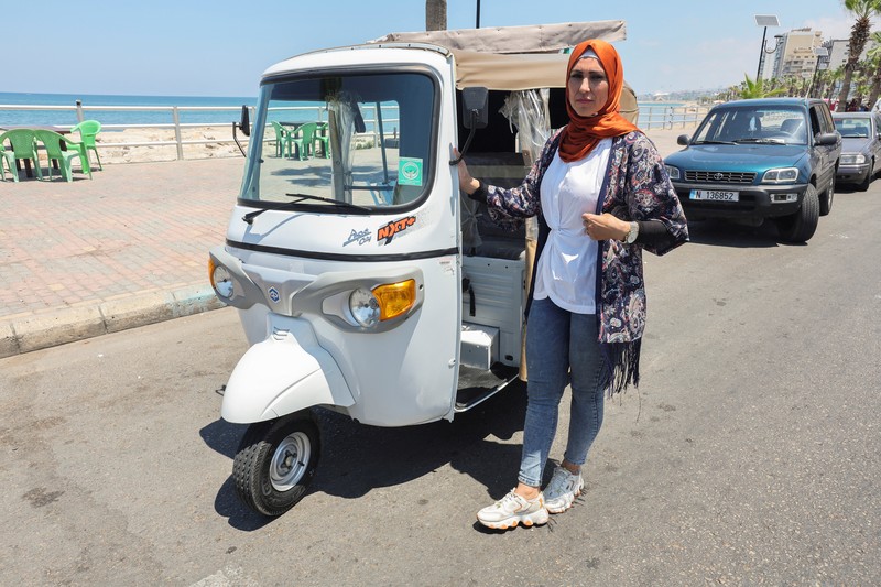 Hala Mohammed al-Yaman, Lebanese mother and tuk-tuk driver, stands next to her tuk-tuk at the corniche in the port city of Sidon, Lebanon June 28, 2022. REUTERS/Aziz Taher