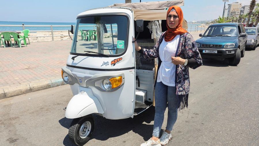 Hala Mohammed al-Yaman, Lebanese mother and tuk-tuk driver, stands next to her tuk-tuk at the corniche in the port city of Sidon, Lebanon June 28, 2022. REUTERS/Aziz Taher