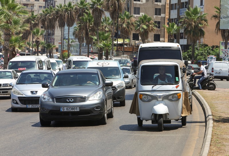 Hala Mohammed al-Yaman, Lebanese mother and tuk-tuk driver, stands next to her tuk-tuk at the corniche in the port city of Sidon, Lebanon June 28, 2022. REUTERS/Aziz Taher