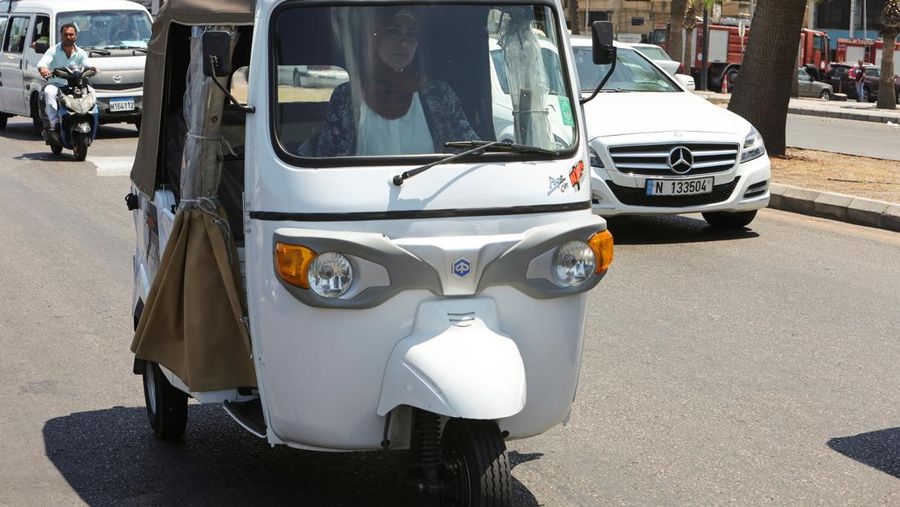 Hala Mohammed al-Yaman, Lebanese mother and tuk-tuk driver, stands next to her tuk-tuk at the corniche in the port city of Sidon, Lebanon June 28, 2022. REUTERS/Aziz Taher