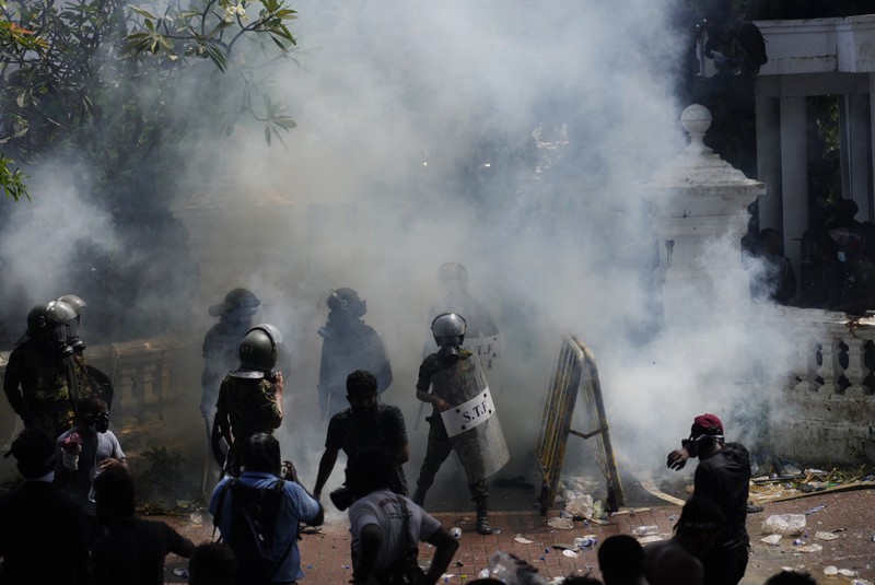 Police use teargas as Sri Lankan protesters storm the compound of prime minister Ranil Wickremesinghe 's office, demanding he resign after president Gotabaya Rajapaksa fled amid economic crisis in Colombo, Sri Lanka, Wednesday, July 13, 2022. (AP Photo/Rafiq Maqbool)