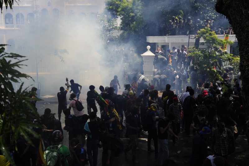 Police use teargas as Sri Lankan protesters storm the compound of prime minister Ranil Wickremesinghe 's office, demanding he resign after president Gotabaya Rajapaksa fled amid economic crisis in Colombo, Sri Lanka, Wednesday, July 13, 2022. (AP Photo/Rafiq Maqbool)