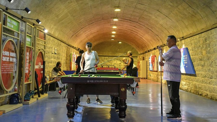 In this photo released by Xinhua News Agency, residents play billiards in an air-raid shelter in Jinan, eastern China's Shandong Province, July 8, 2022. Due to hot weather this summer, Jinan has opened nine air-raid shelters for free, providing citizens with leisure, reading, sports and fitness services. (Zhu Zheng/Xinhua via AP)