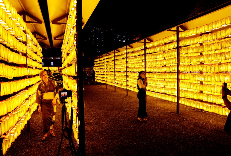 FESTIVAL-JAPAN/ Women in yukata, or casual summer kimonos, wearing protective mask amid the coronavirus disease (COVID-19) outbreak, walk between lanterns during the annual Mitama Festival at the Yasukuni Shrine, where more than 2.4 million war dead are enshrined, in Tokyo, Japan, July 13, 2022. REUTERS/Kim Kyung-Hoon