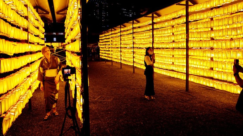 Women in yukata, or casual summer kimonos, wearing protective mask amid the coronavirus disease (COVID-19) outbreak, walk between lanterns during the annual Mitama Festival at the Yasukuni Shrine, where more than 2.4 million war dead are enshrined, in Tokyo, Japan, July 13, 2022. REUTERS/Kim Kyung-Hoon