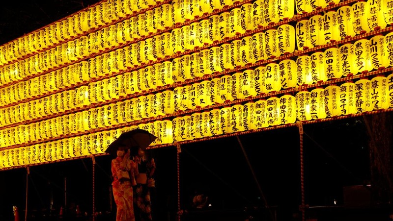 Women in yukata, or casual summer kimonos, wearing protective mask amid the coronavirus disease (COVID-19) outbreak, walk between lanterns during the annual Mitama Festival at the Yasukuni Shrine, where more than 2.4 million war dead are enshrined, in Tokyo, Japan, July 13, 2022. REUTERS/Kim Kyung-Hoon