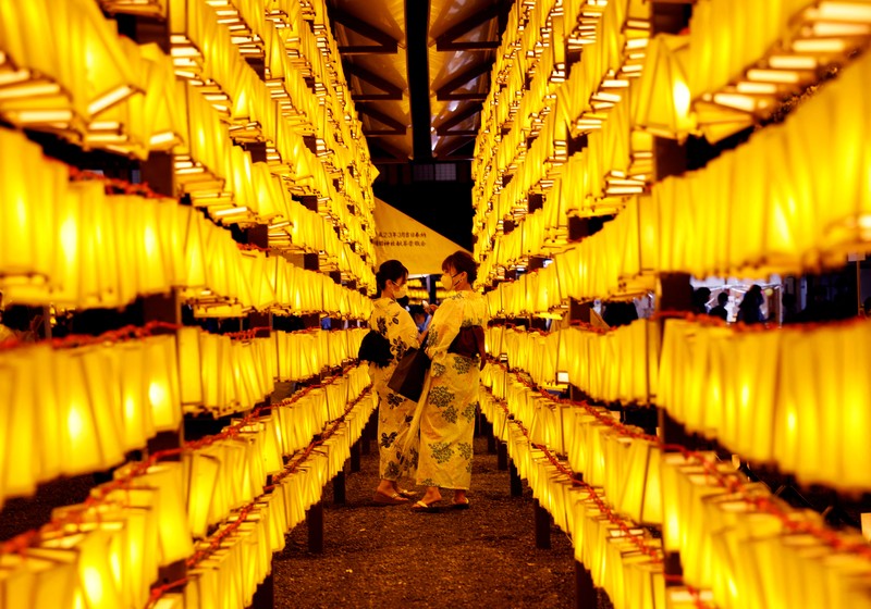 FESTIVAL-JAPAN/ Women in yukata, or casual summer kimonos, wearing protective mask amid the coronavirus disease (COVID-19) outbreak, walk between lanterns during the annual Mitama Festival at the Yasukuni Shrine, where more than 2.4 million war dead are enshrined, in Tokyo, Japan, July 13, 2022. REUTERS/Kim Kyung-Hoon