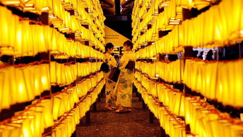 Women in yukata, or casual summer kimonos, wearing protective mask amid the coronavirus disease (COVID-19) outbreak, walk between lanterns during the annual Mitama Festival at the Yasukuni Shrine, where more than 2.4 million war dead are enshrined, in Tokyo, Japan, July 13, 2022. REUTERS/Kim Kyung-Hoon