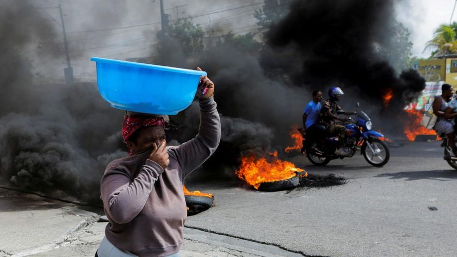 A woman covers her nose while walking past a burning road block as anger mounted over fuel shortages that have intensified as a result of gang violence, in Port-au-Prince, Haiti, July 13, 2022. REUTERS/Ralph Tedy Erol REFILE - QUALITY REPEAT