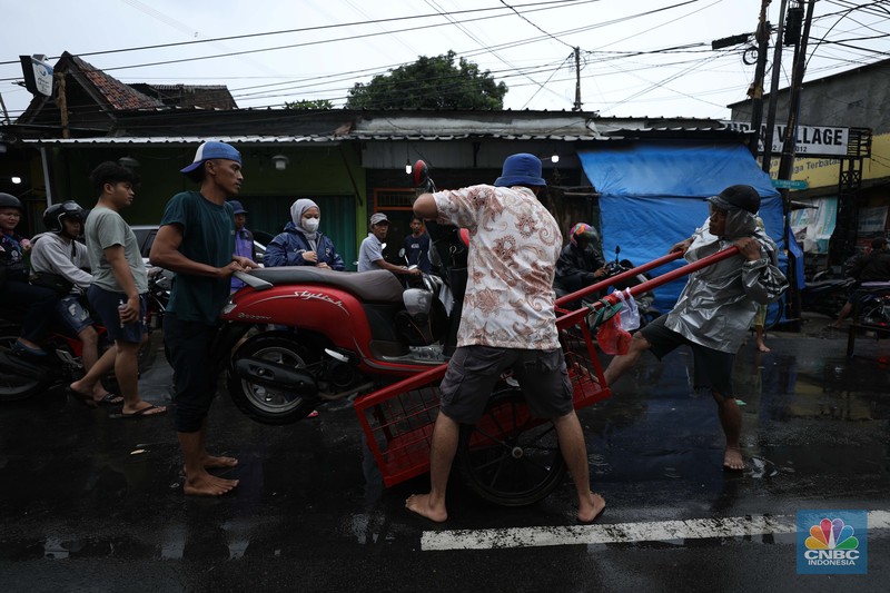 Pengendara sepeda motor menggunakan jasa gerobak saat melintasi banjir di Ciledug, Tangerang Banten, Sabtu (16/7/2022). (CNBC Indonesia/Tri Susilo)