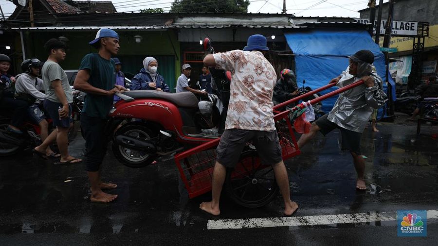 Pengendara sepeda motor menggunakan jasa gerobak saat melintasi banjir di Ciledug, Tangerang Banten, Sabtu (16/7/2022). (CNBC Indonesia/Tri Susilo)