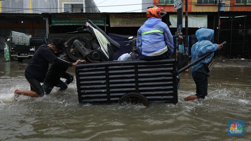 Pengendara sepeda motor menggunakan jasa gerobak saat melintasi banjir di Ciledug, Tangerang Banten, Sabtu (16/7/2022). (CNBC Indonesia/Tri Susilo)
