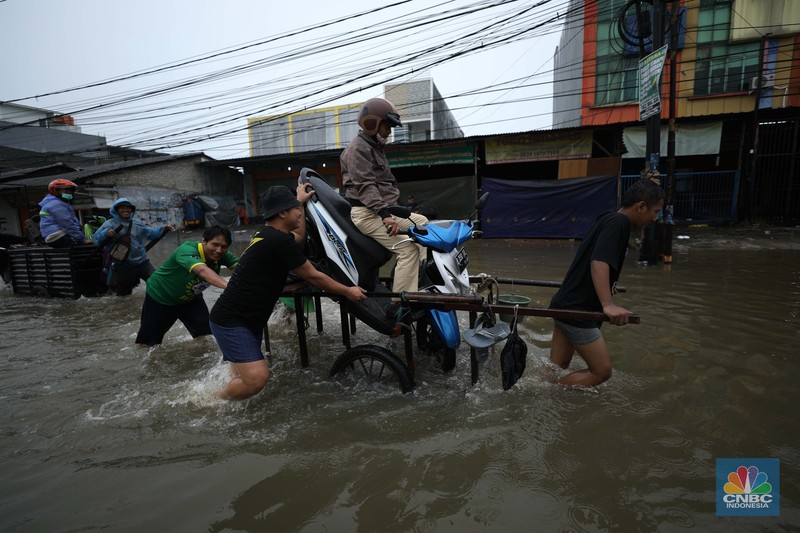 Pengendara sepeda motor menggunakan jasa gerobak saat melintasi banjir di Ciledug, Tangerang Banten, Sabtu (16/7/2022). (CNBC Indonesia/Tri Susilo)