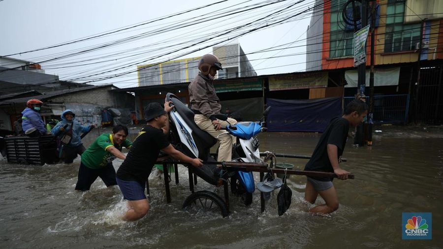 Pengendara sepeda motor menggunakan jasa gerobak saat melintasi banjir di Ciledug, Tangerang Banten, Sabtu (16/7/2022). (CNBC Indonesia/Tri Susilo)