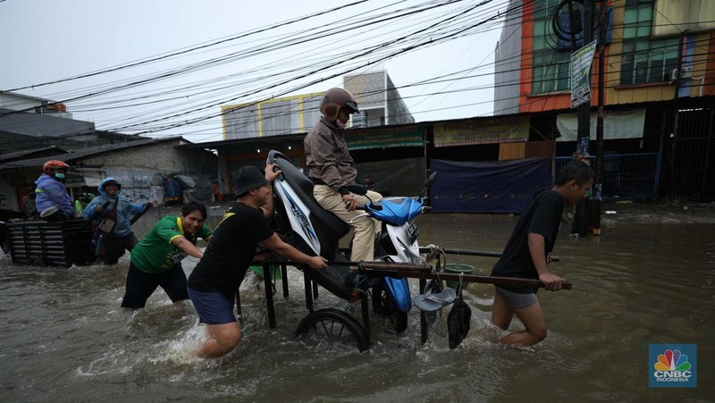 Pengendara sepeda motor menggunakan jasa gerobak saat melintasi banjir di Ciledug, Tangerang Banten, Sabtu (16/7/2022). (CNBC Indonesia/Tri Susilo)