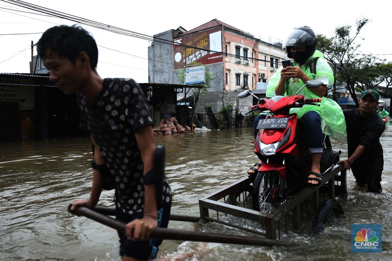 Pengendara sepeda motor menggunakan jasa gerobak saat melintasi banjir di Ciledug, Tangerang Banten, Sabtu (16/7/2022). (CNBC Indonesia/Tri Susilo) Pengendara sepeda motor menggunakan jasa gerobak saat melintasi banjir di Ciledug, Tangerang Banten, Sabtu (16/7/2022). (CNBC Indonesia/Tri Susilo)