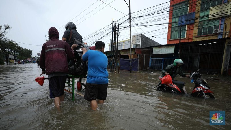 Pengendara sepeda motor menggunakan jasa gerobak saat melintasi banjir di Ciledug, Tangerang Banten, Sabtu (16/7/2022). (CNBC Indonesia/Tri Susilo)