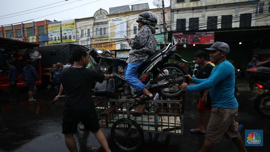Pengendara sepeda motor menggunakan jasa gerobak saat melintasi banjir di Ciledug, Tangerang Banten, Sabtu (16/7/2022). (CNBC Indonesia/Tri Susilo)
