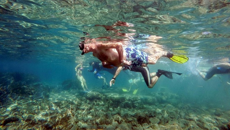 Orang-orang bersiap untuk mengunjungi taman arkeologi bawah laut di pelabuhan kuno Amathus di Limassol, Siprus, Sabtu (9/7/2022). (REUTERS/Yiannis Kourtoglou)