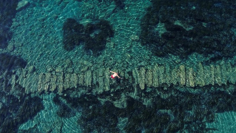 Orang-orang bersiap untuk mengunjungi taman arkeologi bawah laut di pelabuhan kuno Amathus di Limassol, Siprus, Sabtu (9/7/2022). (REUTERS/Yiannis Kourtoglou)