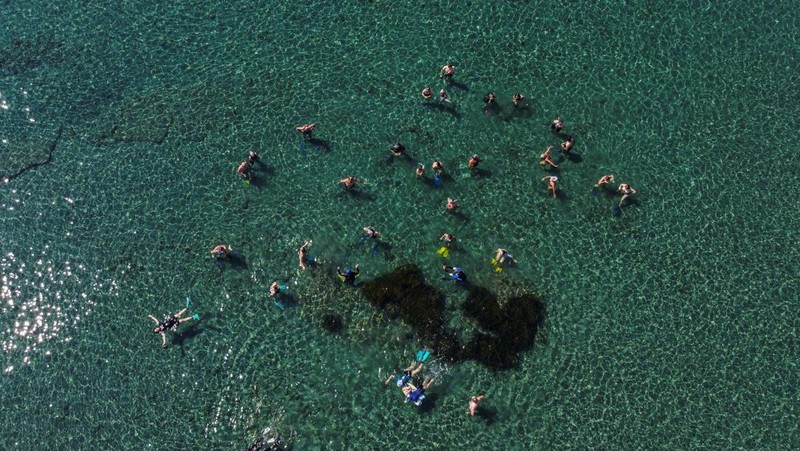 Orang-orang bersiap untuk mengunjungi taman arkeologi bawah laut di pelabuhan kuno Amathus di Limassol, Siprus, Sabtu (9/7/2022). (REUTERS/Yiannis Kourtoglou)