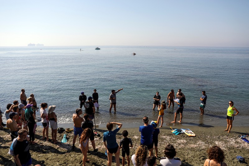 Orang-orang bersiap untuk mengunjungi taman arkeologi bawah laut di pelabuhan kuno Amathus di Limassol, Siprus, Sabtu (9/7/2022). (REUTERS/Yiannis Kourtoglou)