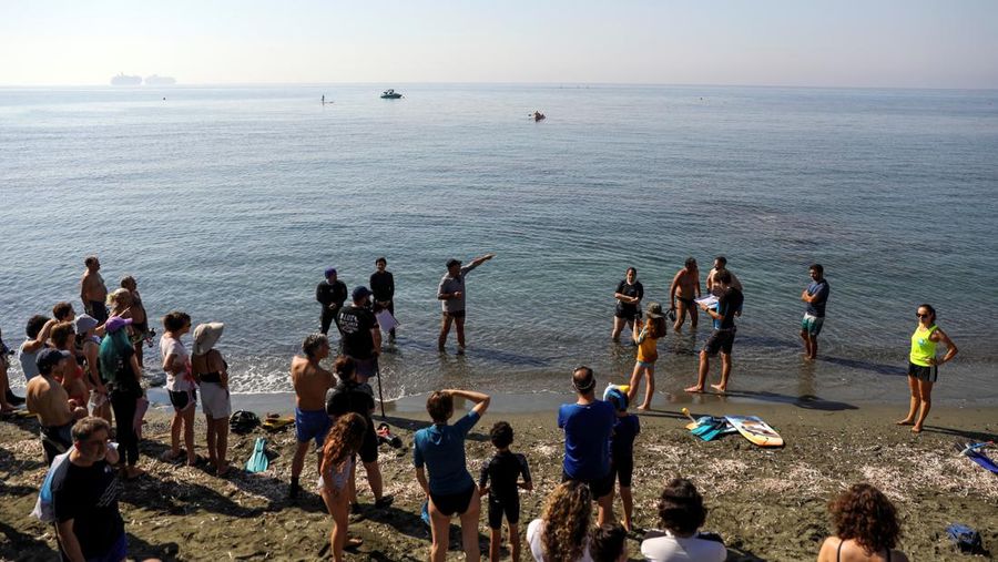 Orang-orang bersiap untuk mengunjungi taman arkeologi bawah laut di pelabuhan kuno Amathus di Limassol, Siprus, Sabtu (9/7/2022). (REUTERS/Yiannis Kourtoglou)
