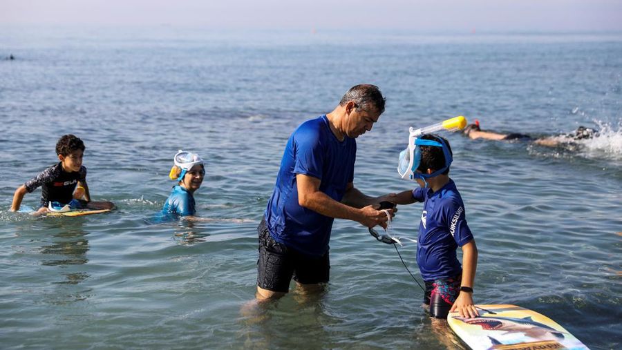 Orang-orang bersiap untuk mengunjungi taman arkeologi bawah laut di pelabuhan kuno Amathus di Limassol, Siprus, Sabtu (9/7/2022). (REUTERS/Yiannis Kourtoglou)
