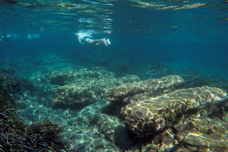 Orang-orang bersiap untuk mengunjungi taman arkeologi bawah laut di pelabuhan kuno Amathus di Limassol, Siprus, Sabtu (9/7/2022). (REUTERS/Yiannis Kourtoglou)