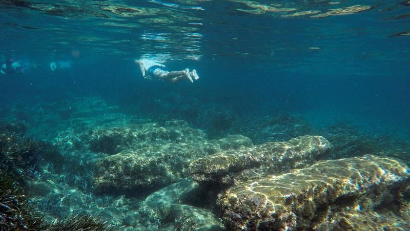 Orang-orang bersiap untuk mengunjungi taman arkeologi bawah laut di pelabuhan kuno Amathus di Limassol, Siprus, Sabtu (9/7/2022). (REUTERS/Yiannis Kourtoglou)