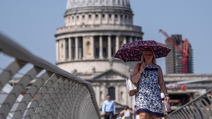 Seorang wanita berlindung di bawah payung saat dia berjalan di dekat Katedral St Paul pada 18 Juli 2022 di London, Inggris. (Getty Images/Carl Court)