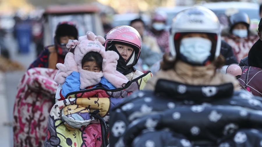 Orang-orang mengenakan pakaian hangat saat berkendara di jalan pada 22 November 2021 di Lianyungang, Provinsi Jiangsu, Tiongkok. (VCG via Getty Images/VCG)