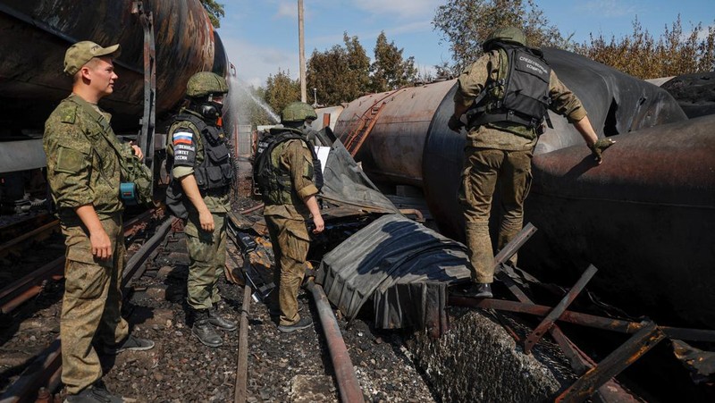 Penyelidik militer Rusia bekerja di lokasi kebakaran di depot minyak di distrik Budyonnovsky di Donetsk, Ukraina, 26 Juli 2022. (REUTERS/STRINGER)