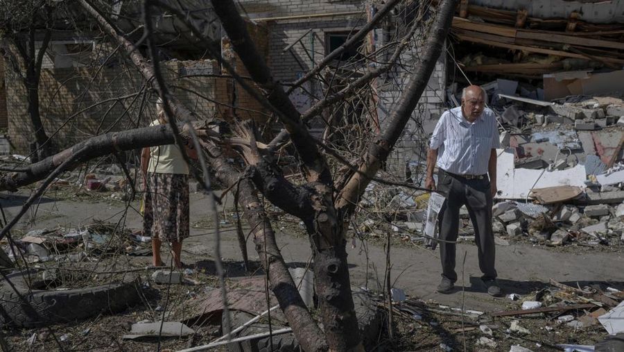 Seorang pria tua berjalan melewati sebuah bangunan yang hancur di Sloviansk di tengah invasi Rusia ke Ukraina, Jumat (29/7/2022). (Photo by BULENT KILIC/AFP via Getty Images)