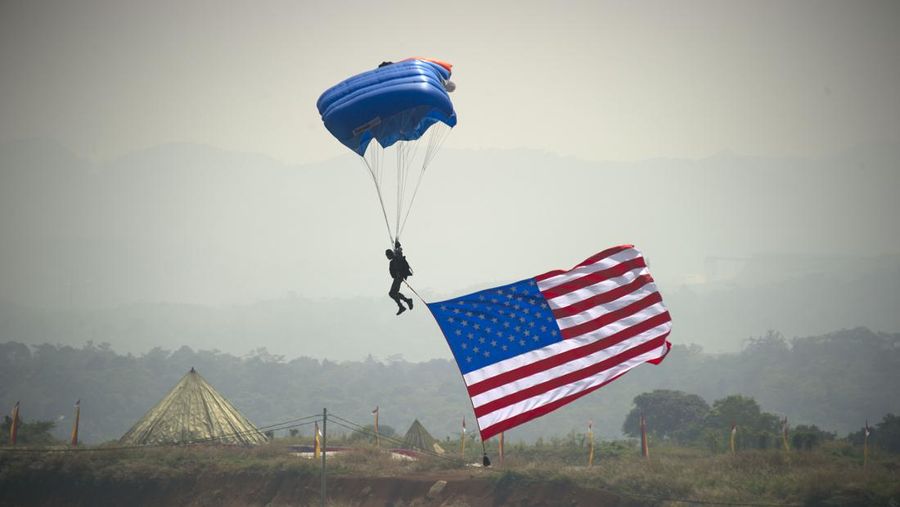 A paratrooper reaches the ground with a US flag during the closing of Counter Terrorism Exercise at Indonesia Peace and Security Center (IPSC) in Sentul, Bogor-West Java, on September 13, 2013. The Counter Terrorism Exercise was followed by 10 ASEAN countries and 8 parther ASEAN countries from September 9, on behalf of ASEAN Defense Minister's Meeting. AFP PHOTO / Bay ISMOYO (Photo credit should read BAY ISMOYO/AFP via Getty Images)