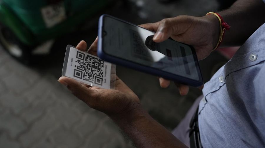 A worker scans a QR code before pumping gas to a vehicle at a fuel station in Colombo, Sri Lanka, Monday, Aug. 1, 2022. Sri Lanka introduced fuel distribution using the QR code Monday as part of implementing a weekly quota for motorists. (AP Photo/Eranga Jayawardena)