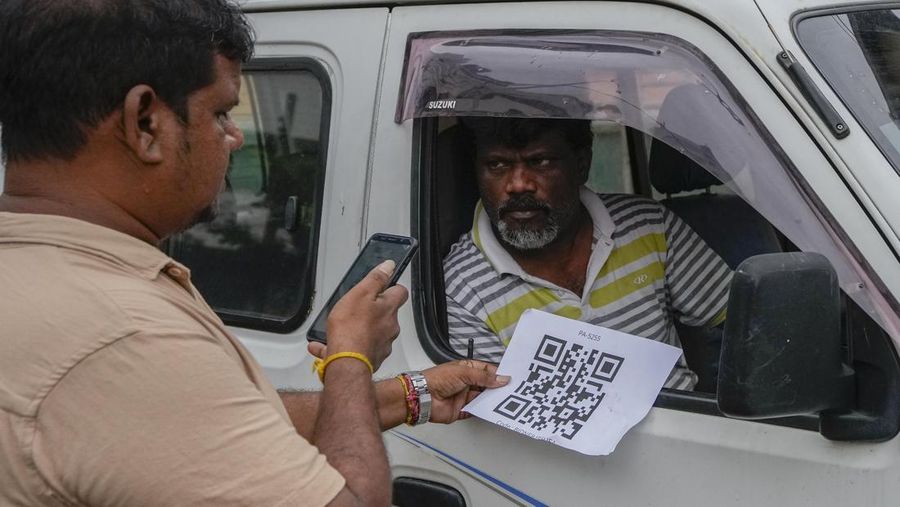 A worker scans a QR code before pumping gas to a vehicle at a fuel station in Colombo, Sri Lanka, Monday, Aug. 1, 2022. Sri Lanka introduced fuel distribution using the QR code Monday as part of implementing a weekly quota for motorists. (AP Photo/Eranga Jayawardena)