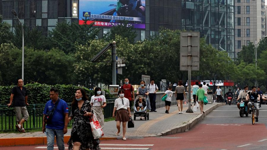 Pejalan kaki berjalan melewati layar raksasa yang menyiarkan laporan berita tentang latihan militer Tentara Pembebasan Rakyat China (PLA) di sekitar Taiwan, di Beijing, China, Kamis (4/8/2022). (REUTERS/Thomas Peter)