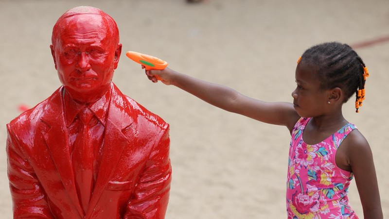 Children put sand on a statue of Russian President Vladimir Putin riding a tank created by French artist James Colomina in Central Park in Manhattan, New York City, U.S., August 2, 2022. REUTERS/Andrew Kelly