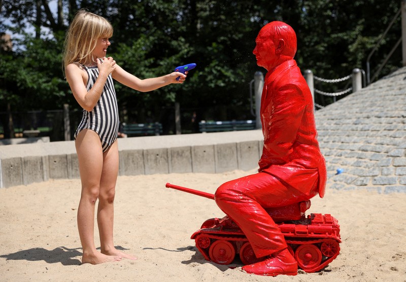 UKRAINE-CRISIS/USA-STATUE Children put sand on a statue of Russian President Vladimir Putin riding a tank created by French artist James Colomina in Central Park in Manhattan, New York City, U.S., August 2, 2022. REUTERS/Andrew Kelly
