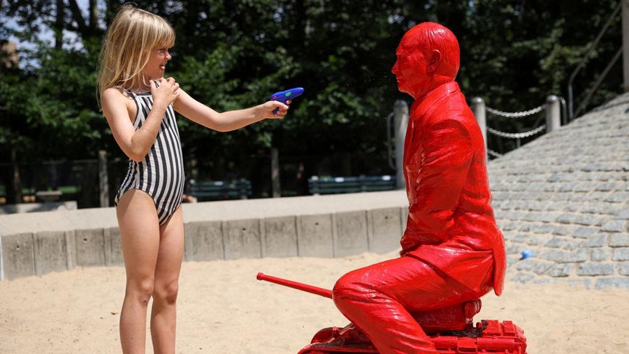 Children put sand on a statue of Russian President Vladimir Putin riding a tank created by French artist James Colomina in Central Park in Manhattan, New York City, U.S., August 2, 2022. REUTERS/Andrew Kelly