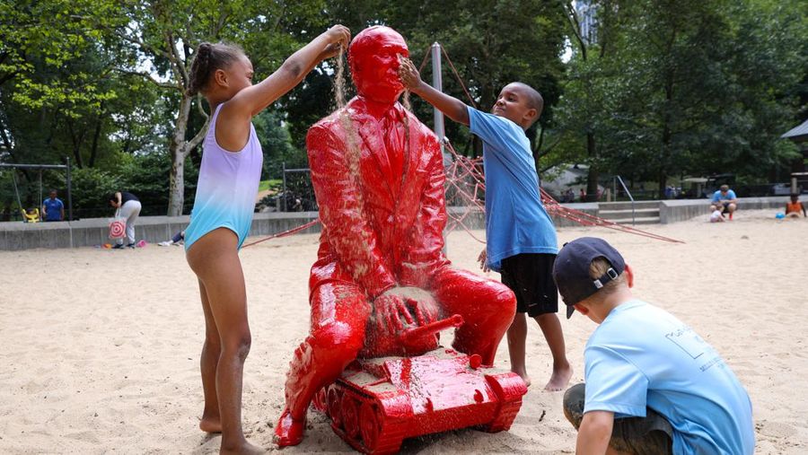 Children put sand on a statue of Russian President Vladimir Putin riding a tank created by French artist James Colomina in Central Park in Manhattan, New York City, U.S., August 2, 2022. REUTERS/Andrew Kelly