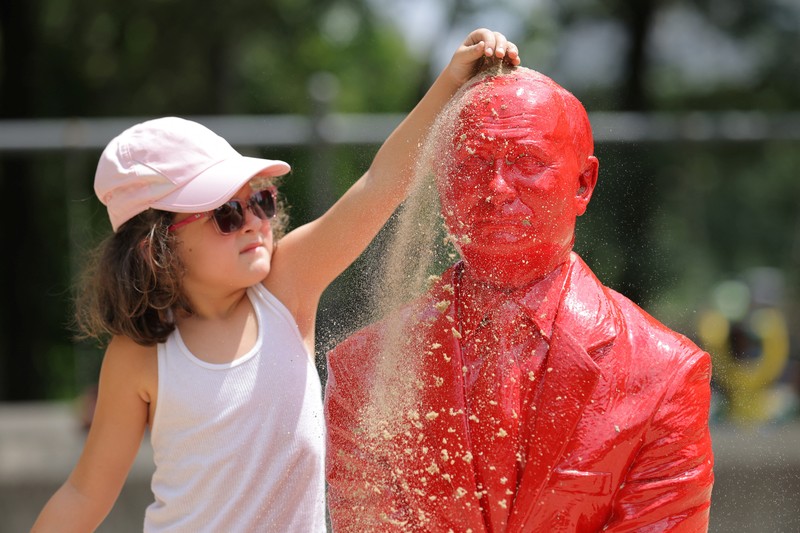 UKRAINE-CRISIS/USA-STATUE Children put sand on a statue of Russian President Vladimir Putin riding a tank created by French artist James Colomina in Central Park in Manhattan, New York City, U.S., August 2, 2022. REUTERS/Andrew Kelly