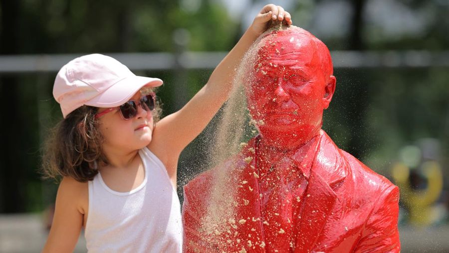 Children put sand on a statue of Russian President Vladimir Putin riding a tank created by French artist James Colomina in Central Park in Manhattan, New York City, U.S., August 2, 2022. REUTERS/Andrew Kelly